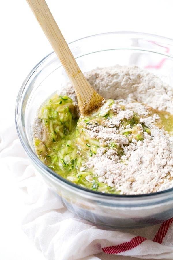 Muffin mix in a clear mixing bowl with a wooden spoon.