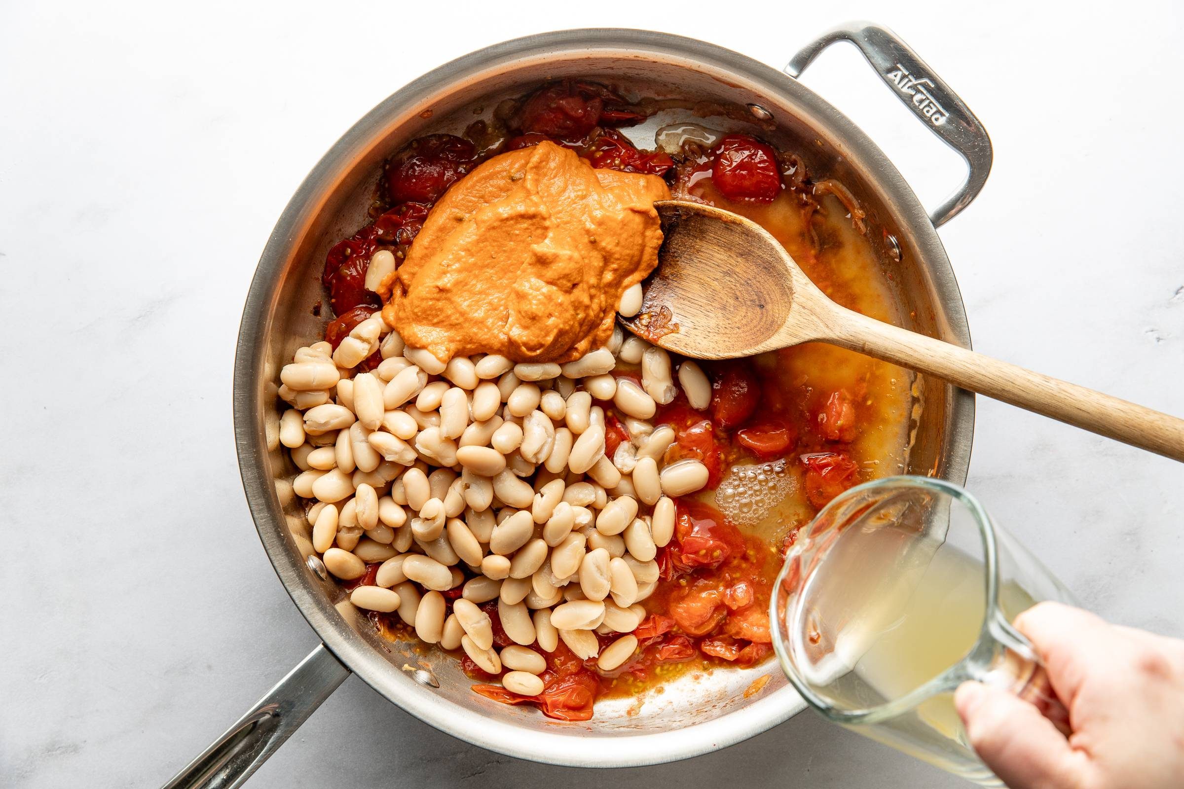Adding beans and sauce to pan.