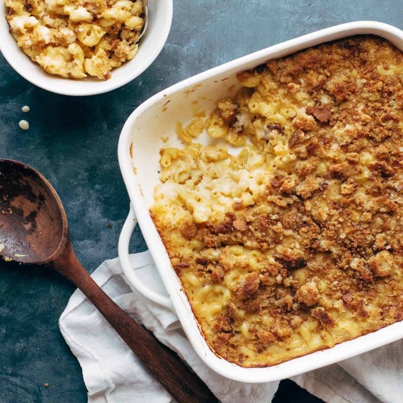 Baked mac and cheese in a pan with a wooden spoon.