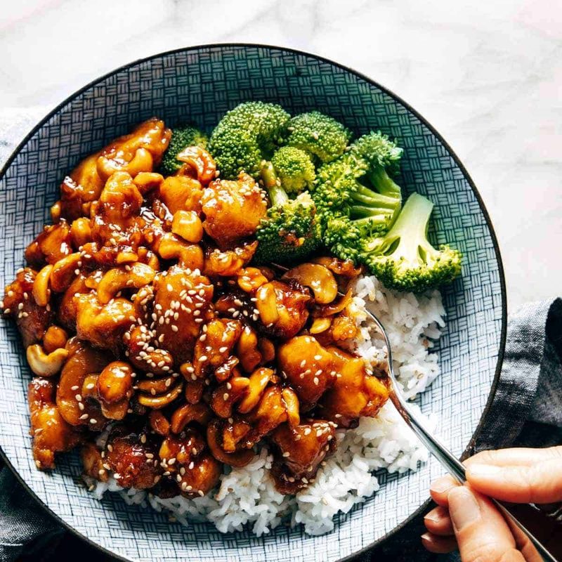 Cashew chicken in a bowl with rice and broccoli.