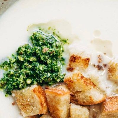 Cheesy Cauliflower Soup in a bowl with pesto and croutons.