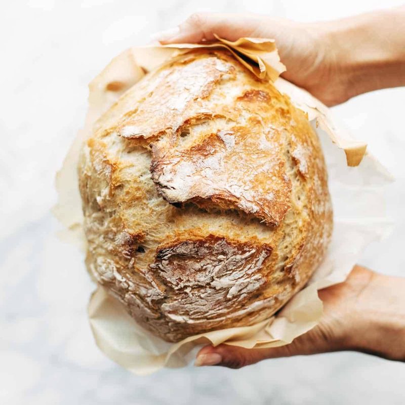 White hands holding homemade no knead bread.
